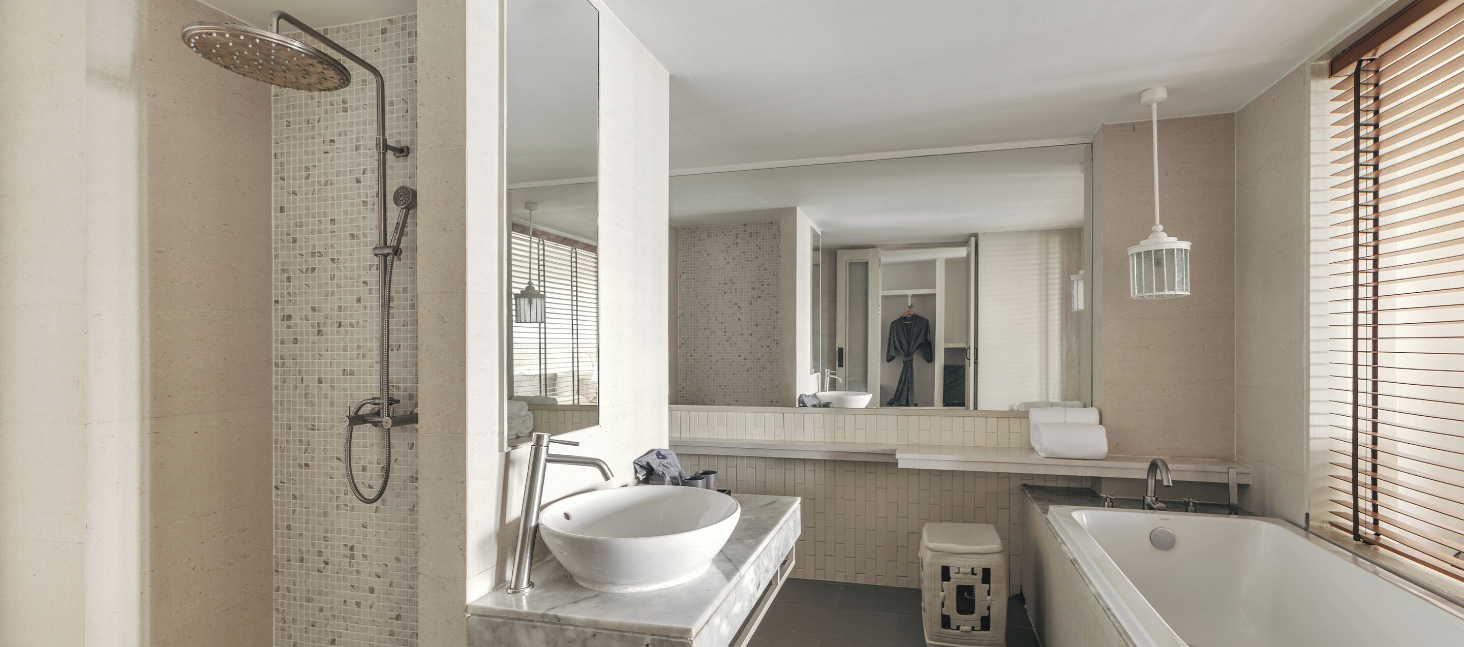 Une salle de bain équipée d’une douche, d’un lavabo et d’une baignoire, ainsi que d’un miroir et d’un luminaire suspendu.