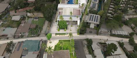 Vista aérea de una zona residencial con un edificio destacado que cuenta con techo plano, piscina y estacionamiento.