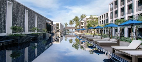 Una piscina al aire libre, sombrillas. AWA Koh Chang