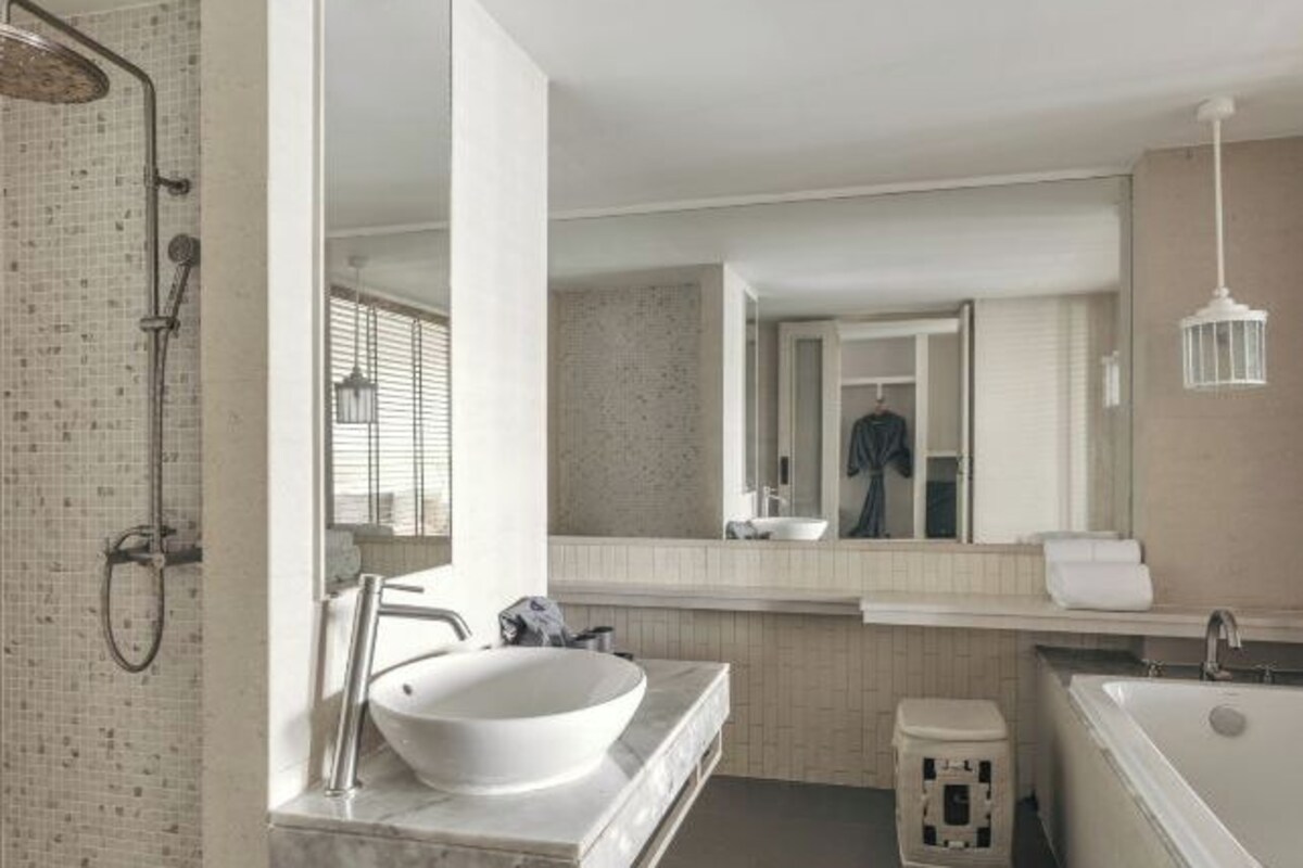 A modern bathroom with a freestanding bathtub, a large mirror, and a shower area.
