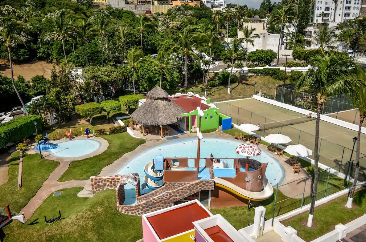 Un parc aquatique doté de plusieurs toboggans, d’une piscine et d’un abri à toit de chaume.