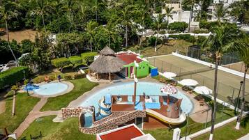 Un parc aquatique doté de plusieurs toboggans, d’une piscine et d’un abri à toit de chaume.