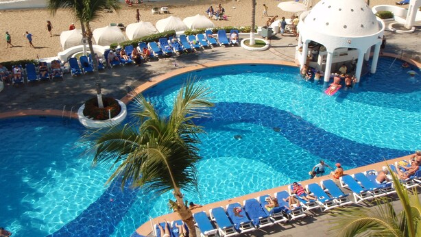 A pool area with lounge chairs and a small pavilion, surrounded by palm trees and a beach. - Sierra Mar Mazanillo (Manzanillo)