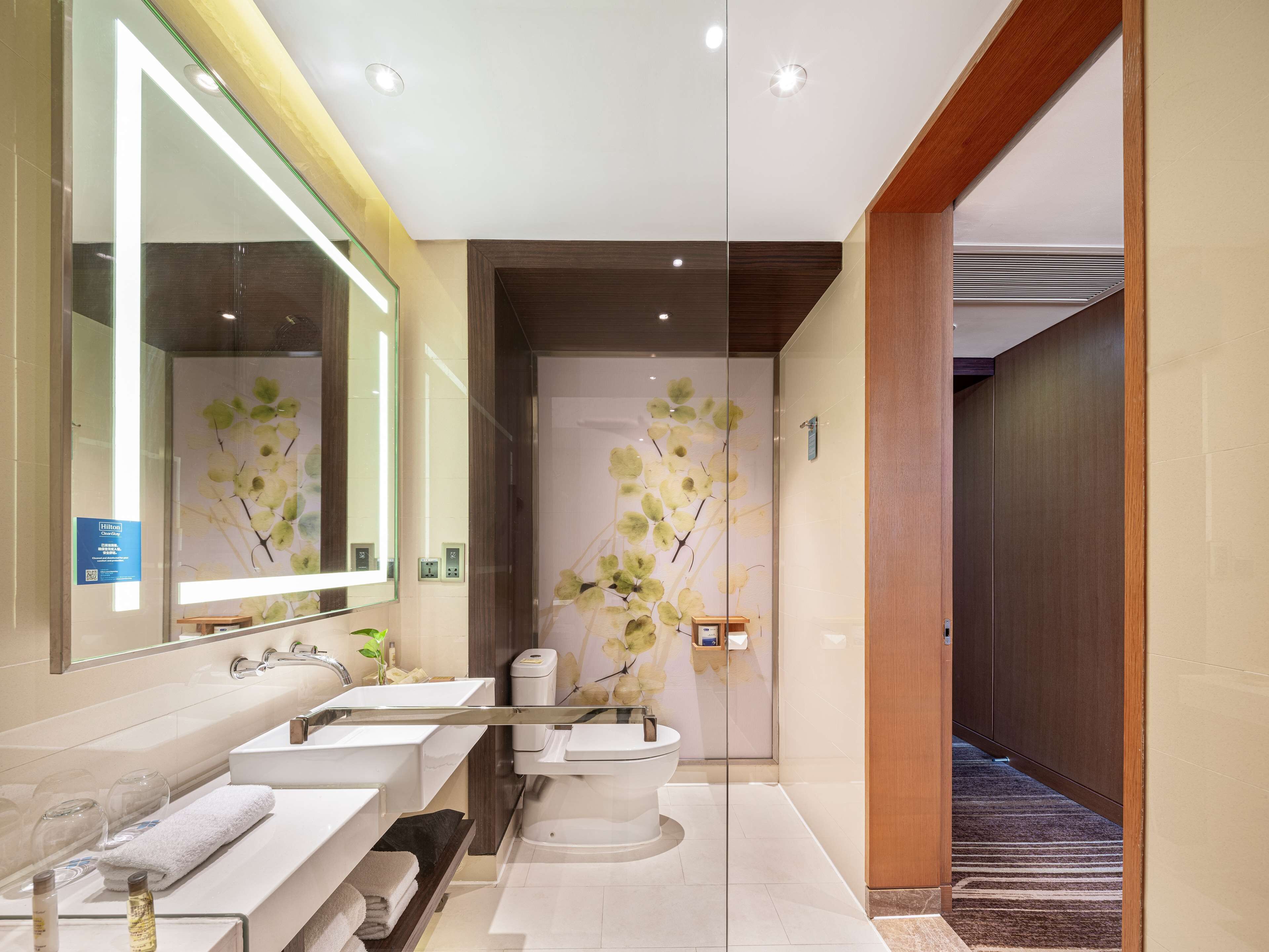 Une salle de bain moderne avec deux lavabos, des toilettes et une douche séparée par une paroi en verre.