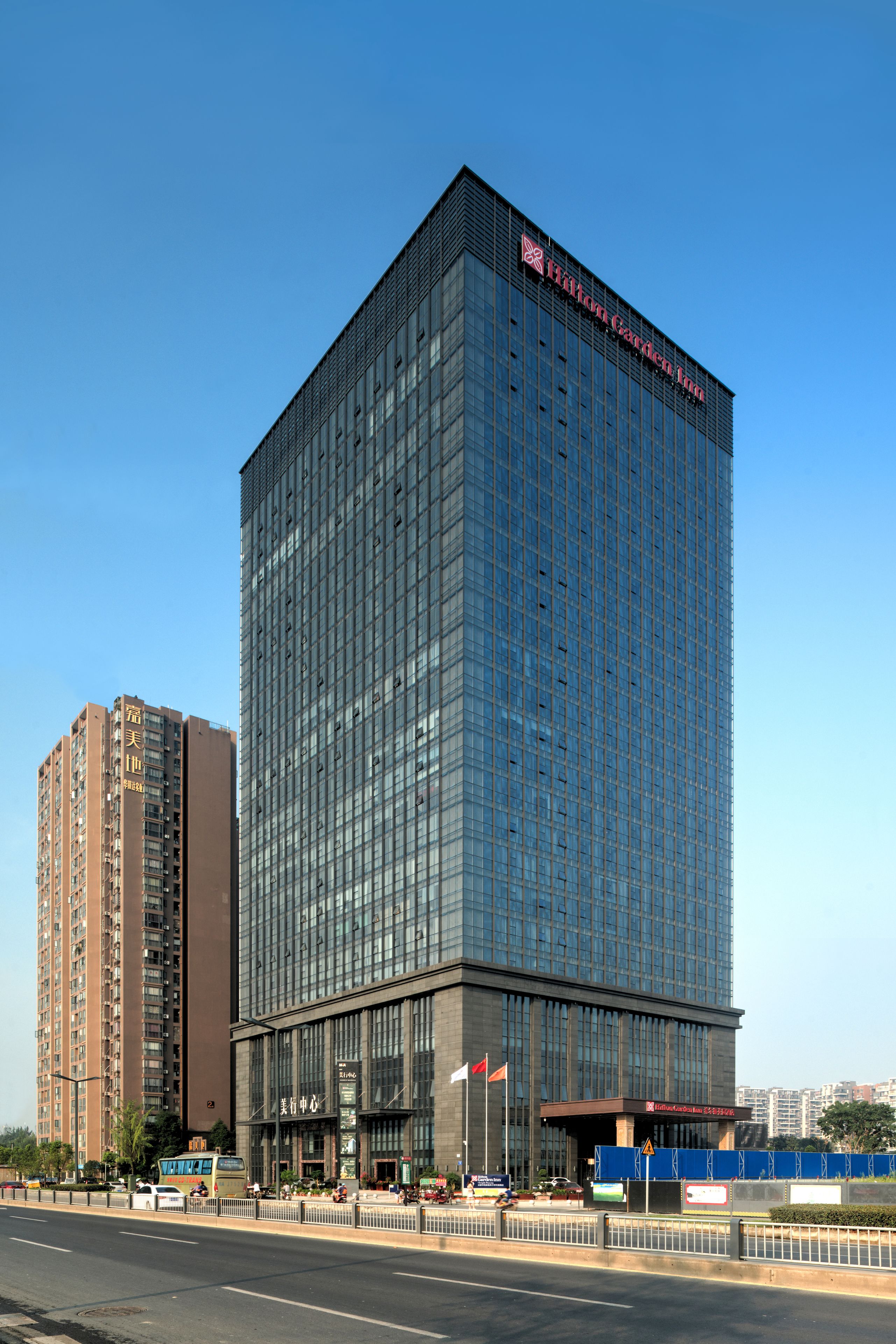 Un hôtel moderne, avec une façade en verre et une enseigne bien visible sur le toit.