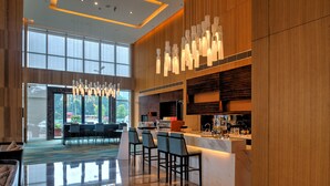 En modern hotellobby med en receptionsdisk, en bardel och sittplatser.