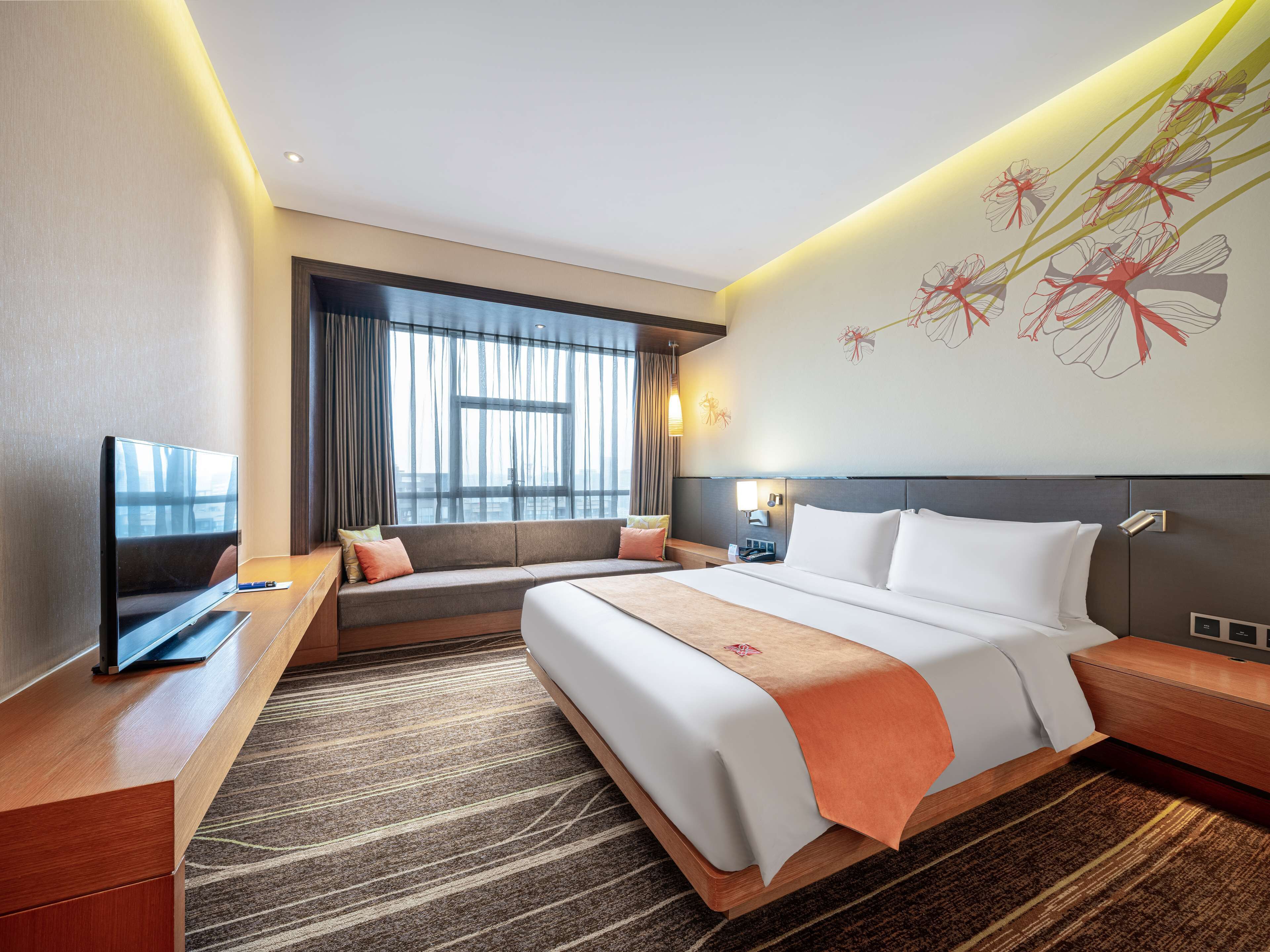 Une chambre d’hôtel avec un grand lit, un canapé, une télévision et une fenêtre avec des rideaux.