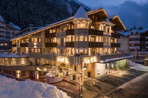 A multi-story hotel with balconies, a covered entrance, and a parking area. - Hotel Seespitz (Ischgl)