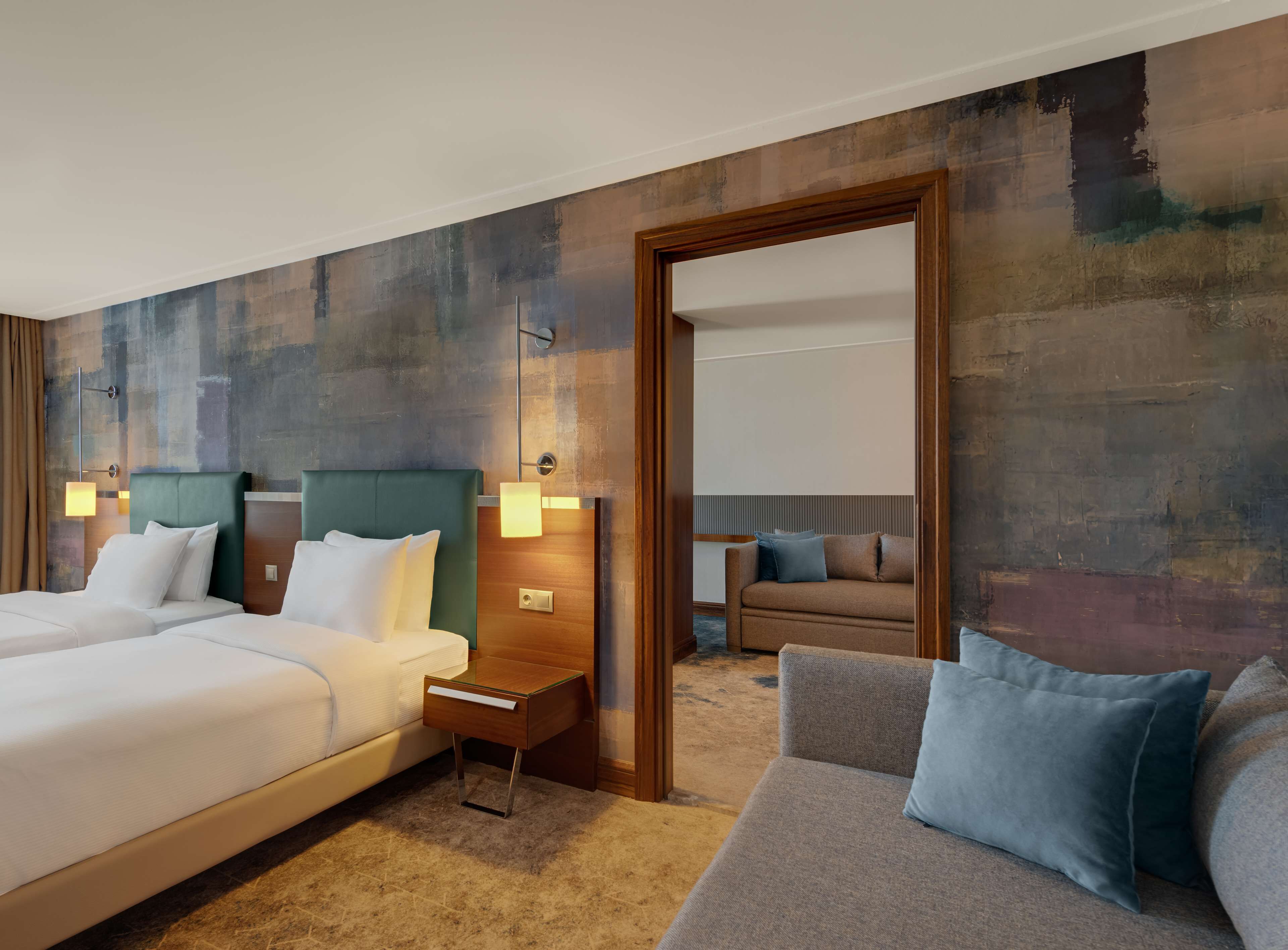 Habitación de hotel con dos camas, un sofá y una puerta de madera.