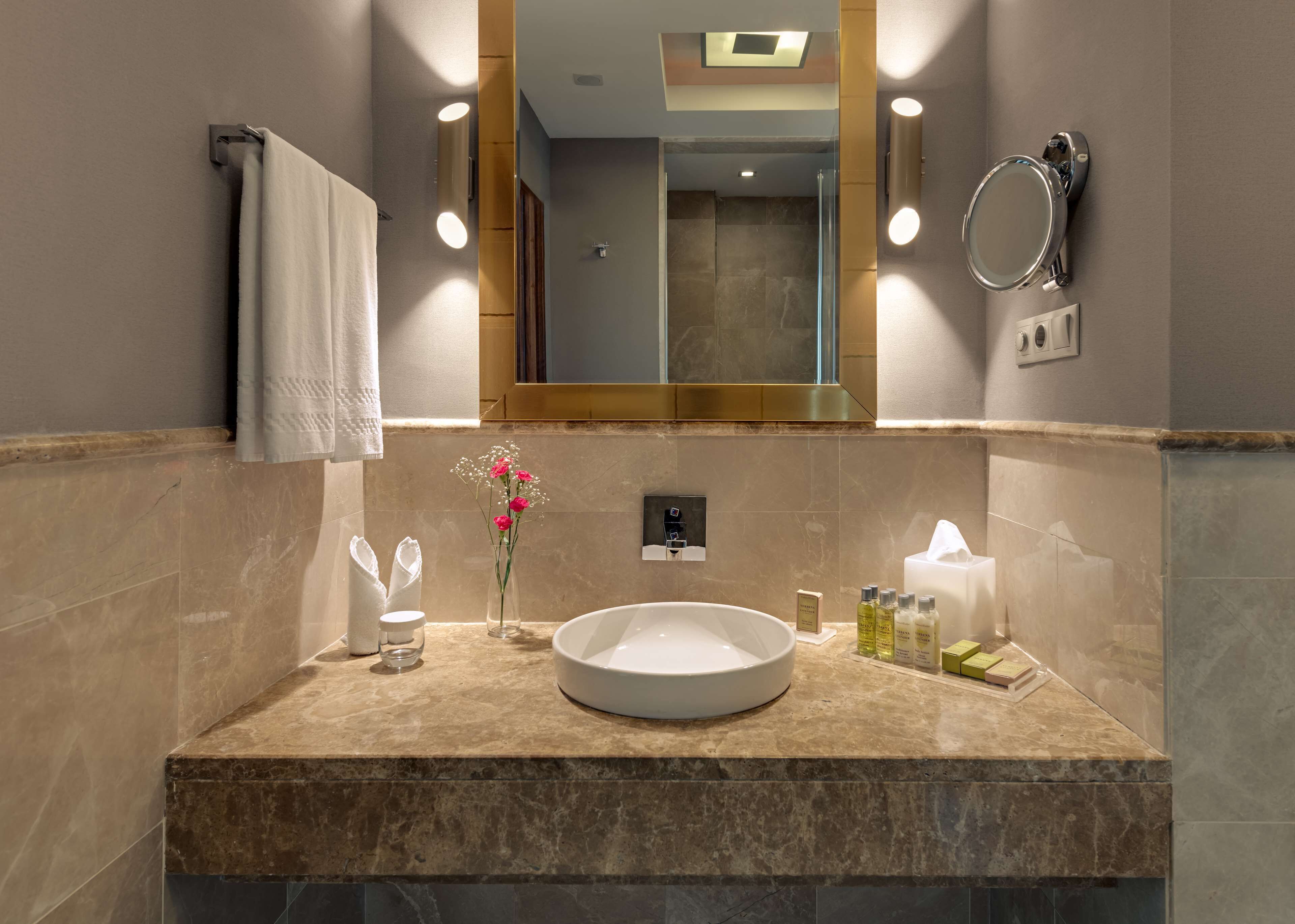 Un baño con un lavabo redondo, un espejo, una toalla y artículos de aseo en la encimera.