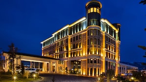 Un hôtel moderne doté d’une tour imposante, de grandes fenêtres et d’une entrée bien éclairée.