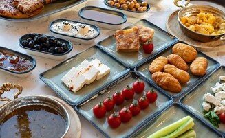 Variedad de alimentos sobre una mesa, como pasteles, queso y tomates.