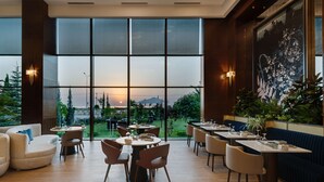 Un restaurant doté de grandes fenêtres, offrant une vue sur le coucher de soleil, et proposant des places assises à l’intérieur.