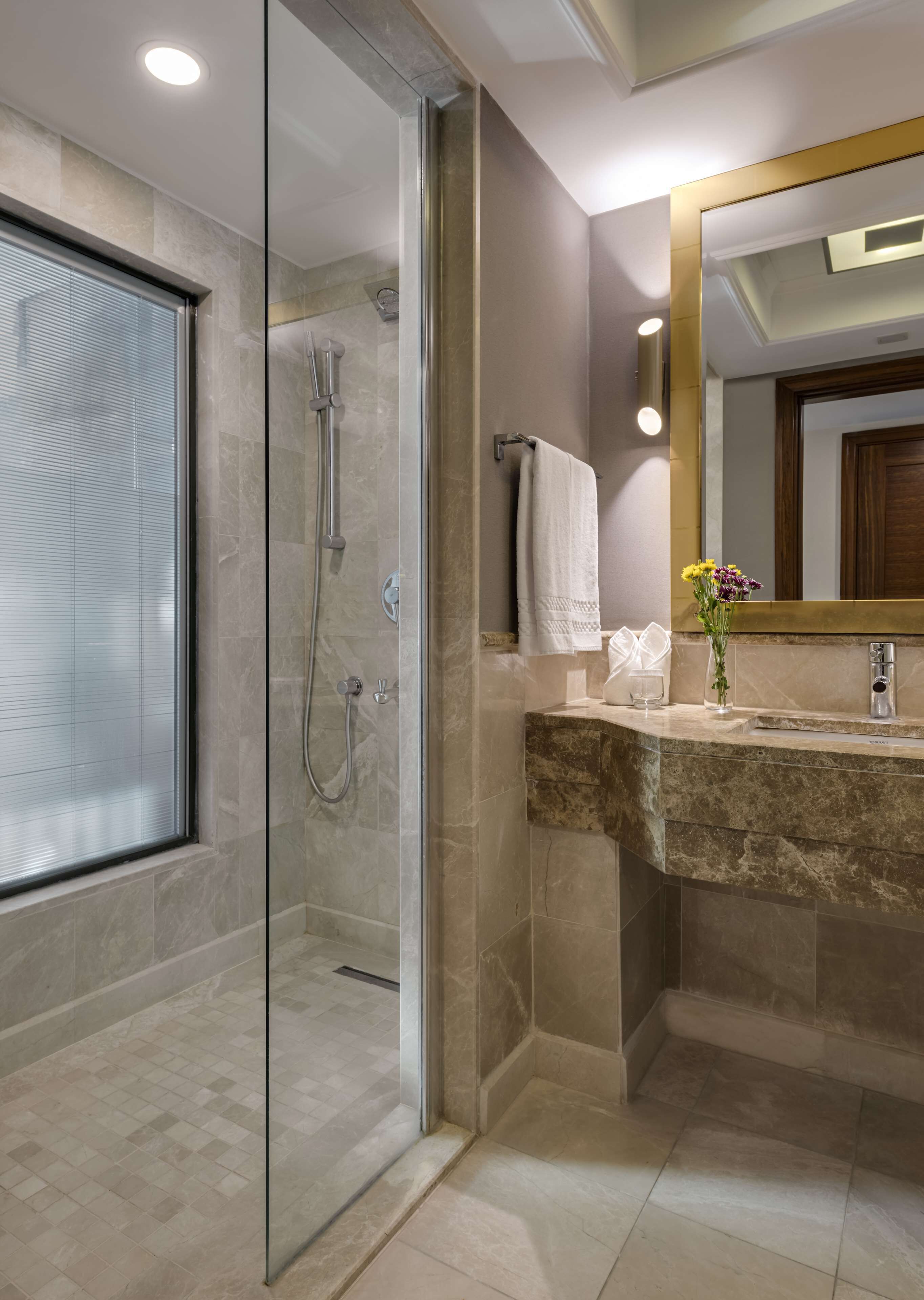 Un bagno moderno con cabina doccia in vetro, lavabo in marmo e uno specchio grande.