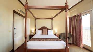 A four-poster bed with a wooden frame, a white bedspread, and a patterned throw.