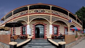 A restaurant and hotel cafe with a curved facade, outdoor seating, and a sign indicating it is open.