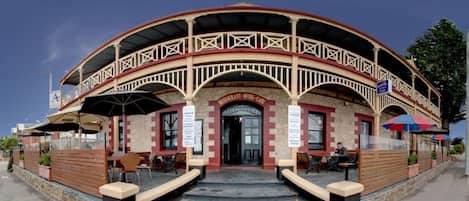 A restaurant and hotel cafe with a curved facade, outdoor seating, and a sign indicating it is open.