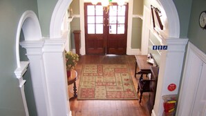 A hallway with a wooden floor, a patterned rug, and a door with glass panels.