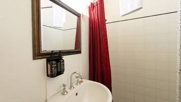 Un baño con lavamanos blanco, espejo y cortina de ducha roja.