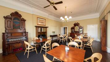 A dining room with a wooden table and chairs, a ceiling fan, and a chandelier.
