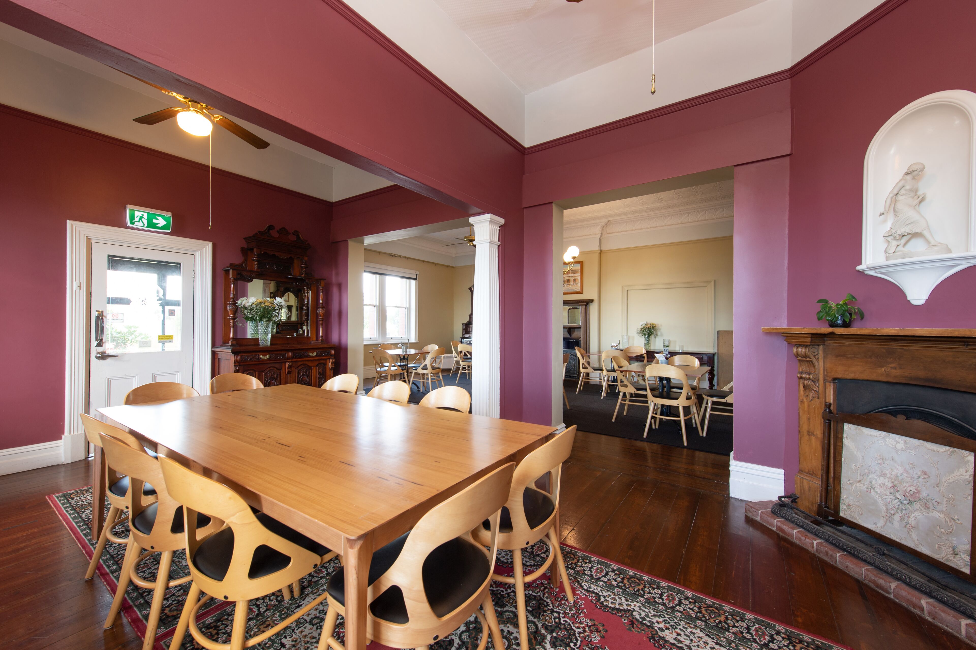 A dining area with a wooden table and chairs, a fireplace, and a view into another room.