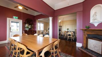 A dining area with a wooden table and chairs, a fireplace, and a view into another room.