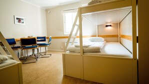 A bunk bed room with a desk and chairs, a window, and a picture on the wall.