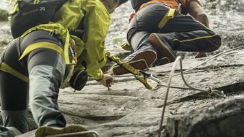 Two people climbing a rocky surface with climbing gear and ropes.
