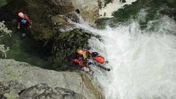 Una persona amb una jaqueta i casc vermells que s'obre pas per una cascada rocosa.