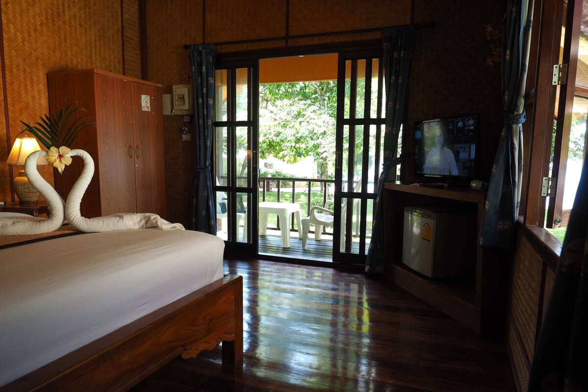 A hotel room with a bed, a television, and a view of the outdoors.