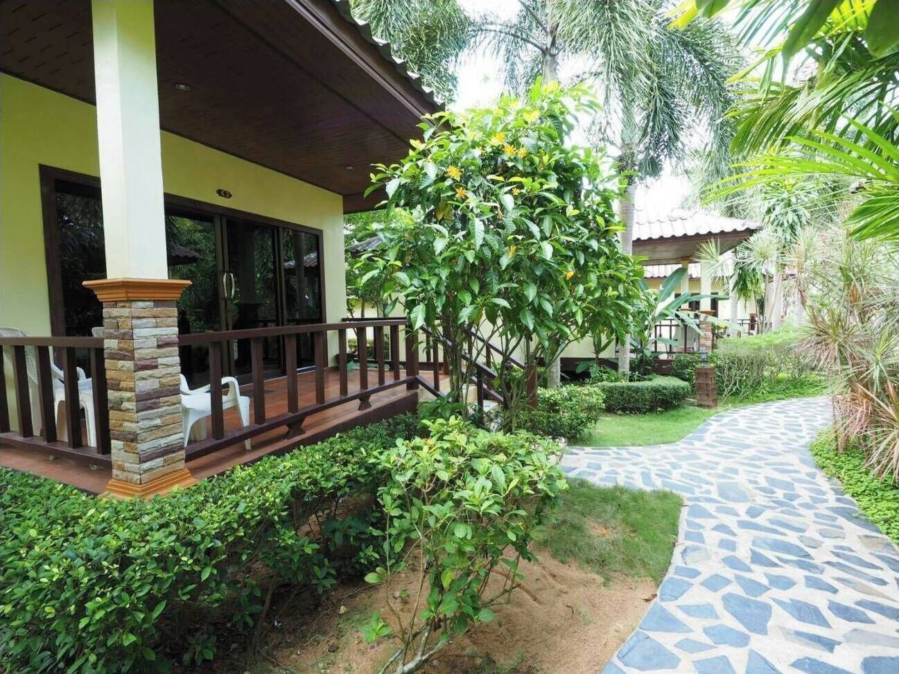 A covered outdoor area with a stone pillar, a wooden deck, and a stone pathway.