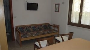 Una habitación con un sofá de madera, una mesita y una ventana con cortinas.
