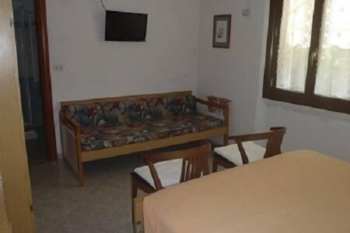 A room with a wooden sofa, a small table, and a window with curtains.