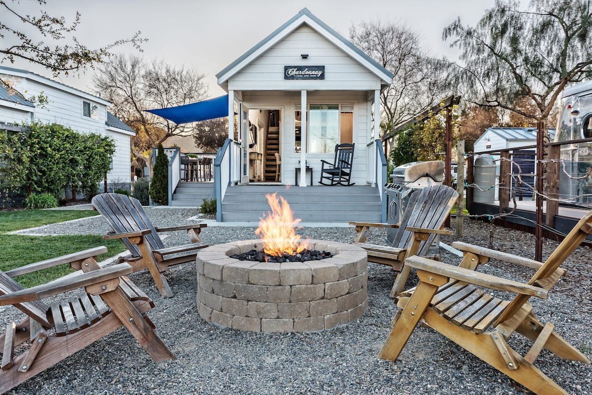 A house with a covered porch, a fire pit, and outdoor seating.