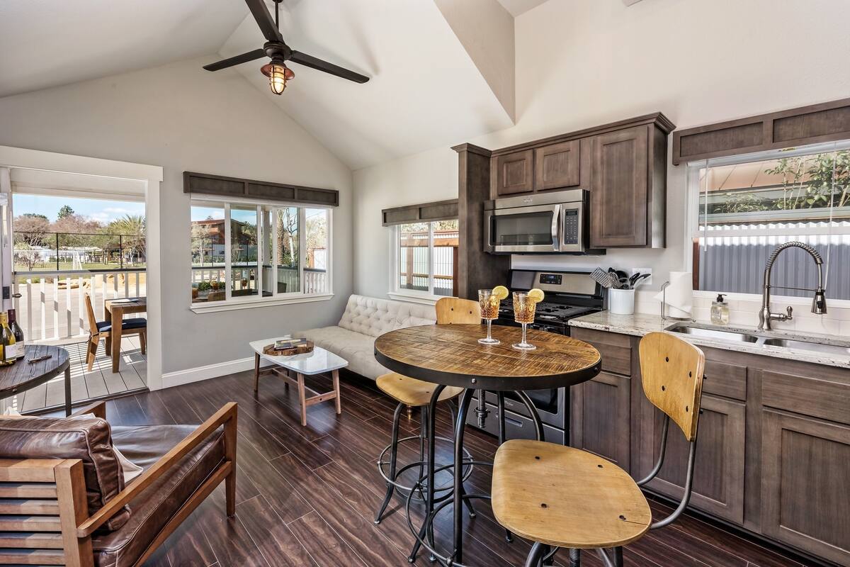 A modern kitchen with dark wood cabinets, a stainless steel microwave, and a large window.