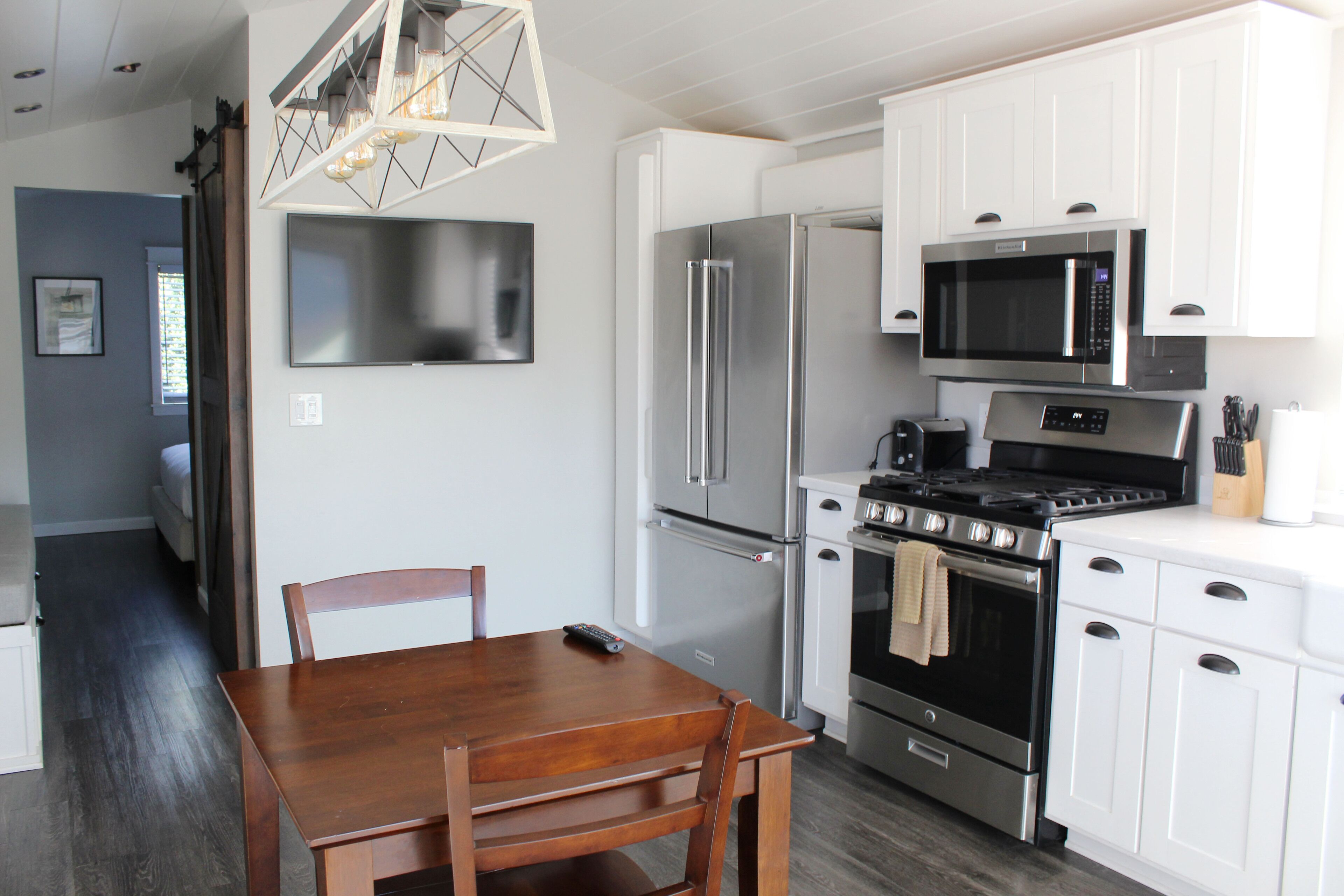 A modern kitchen with white cabinets, stainless steel appliances, and a wooden dining table.