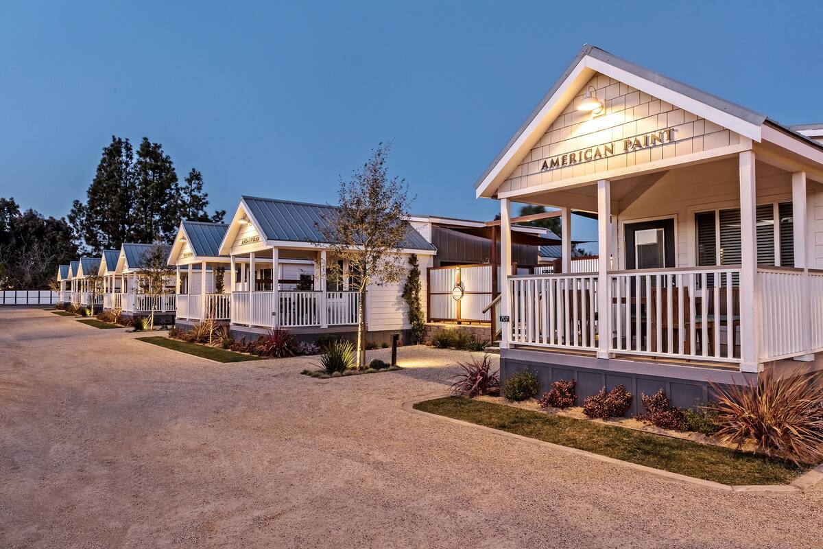 A row of single-story cabins with white railings and a covered porch, labeled "AMERICAN PAINT."