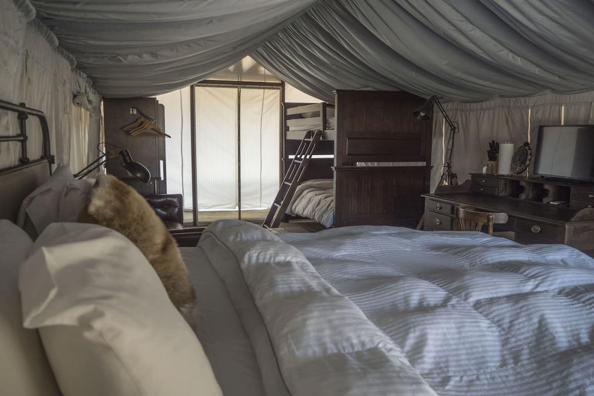 A bedroom with a bunk bed, a desk with a lamp, and a TV.