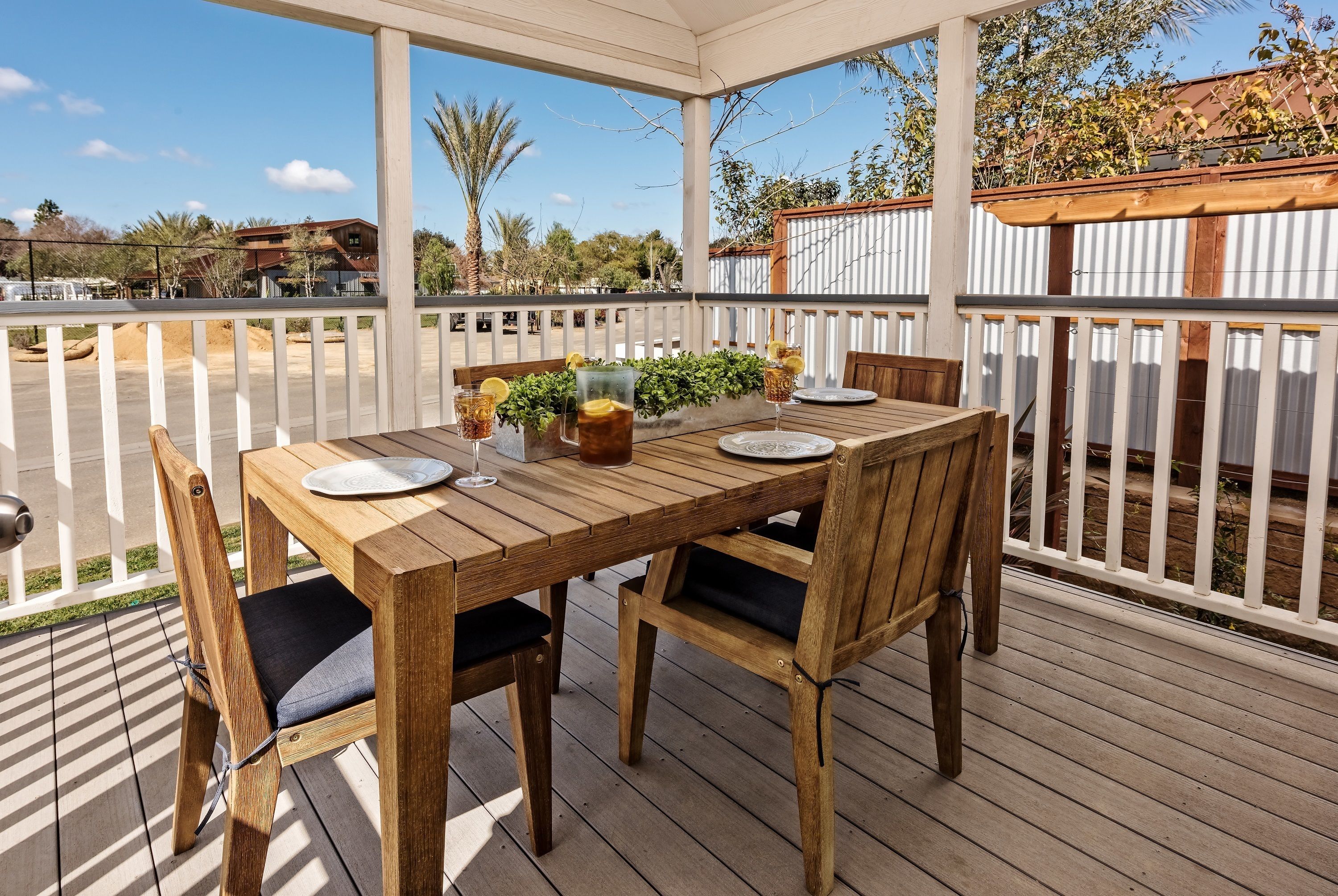 A wooden deck with a table set for two, surrounded by white railings.
