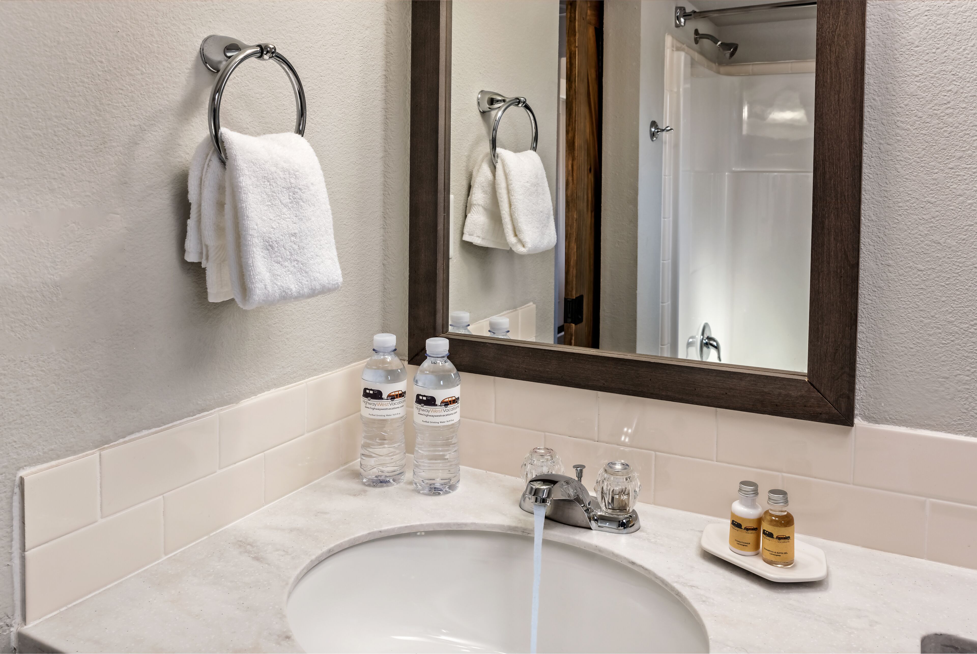 A bathroom with a sink, two bottles of water, and a mirror.