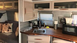 Una kitchenette pequeña con un lavamanos, estufa y alacenas.