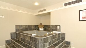 Un baño moderno con una bañera independiente grande, una zona de ducha con azulejos y un pequeño espejo decorativo.