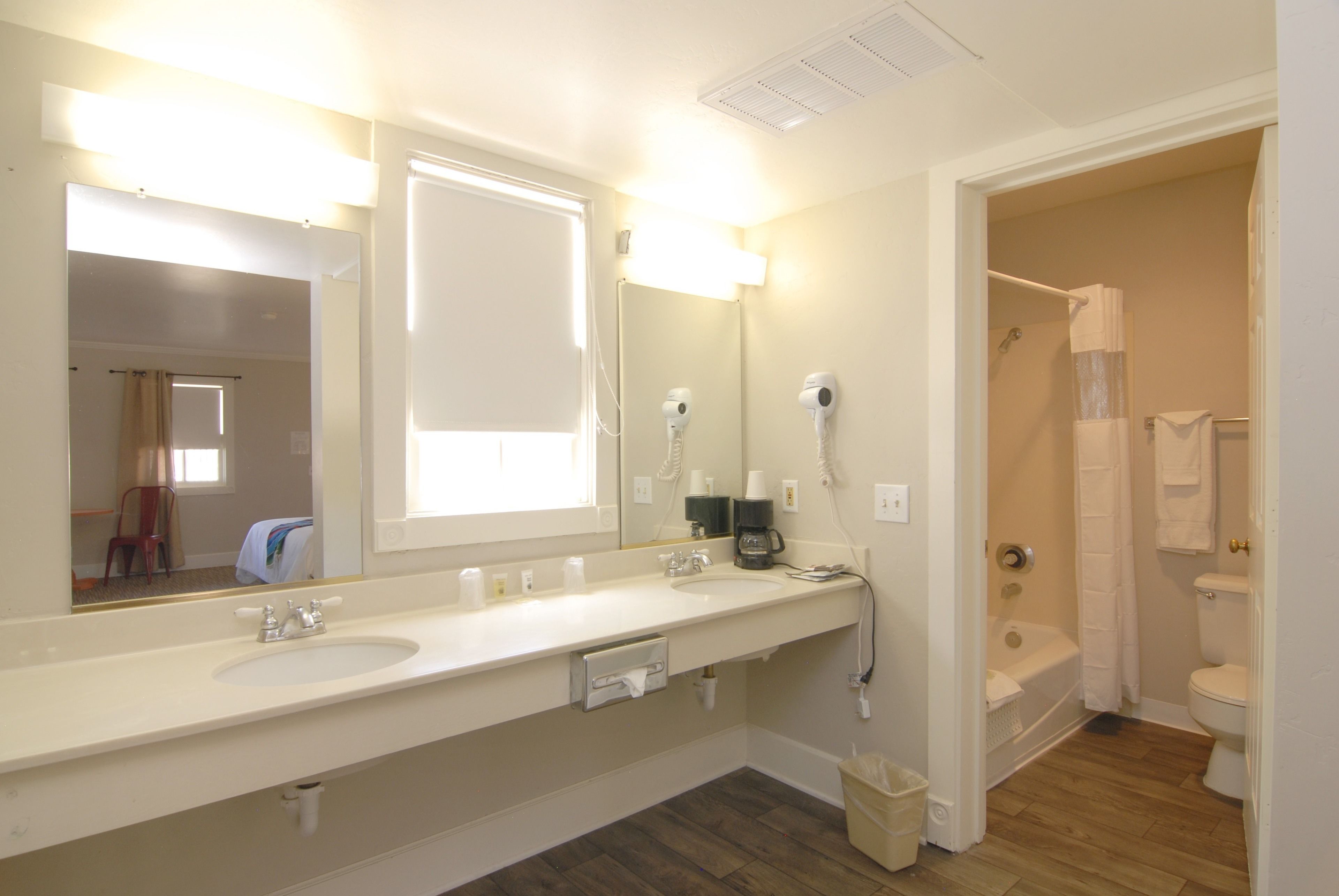 A bathroom with a double sink, a large mirror, a shower, and a toilet.