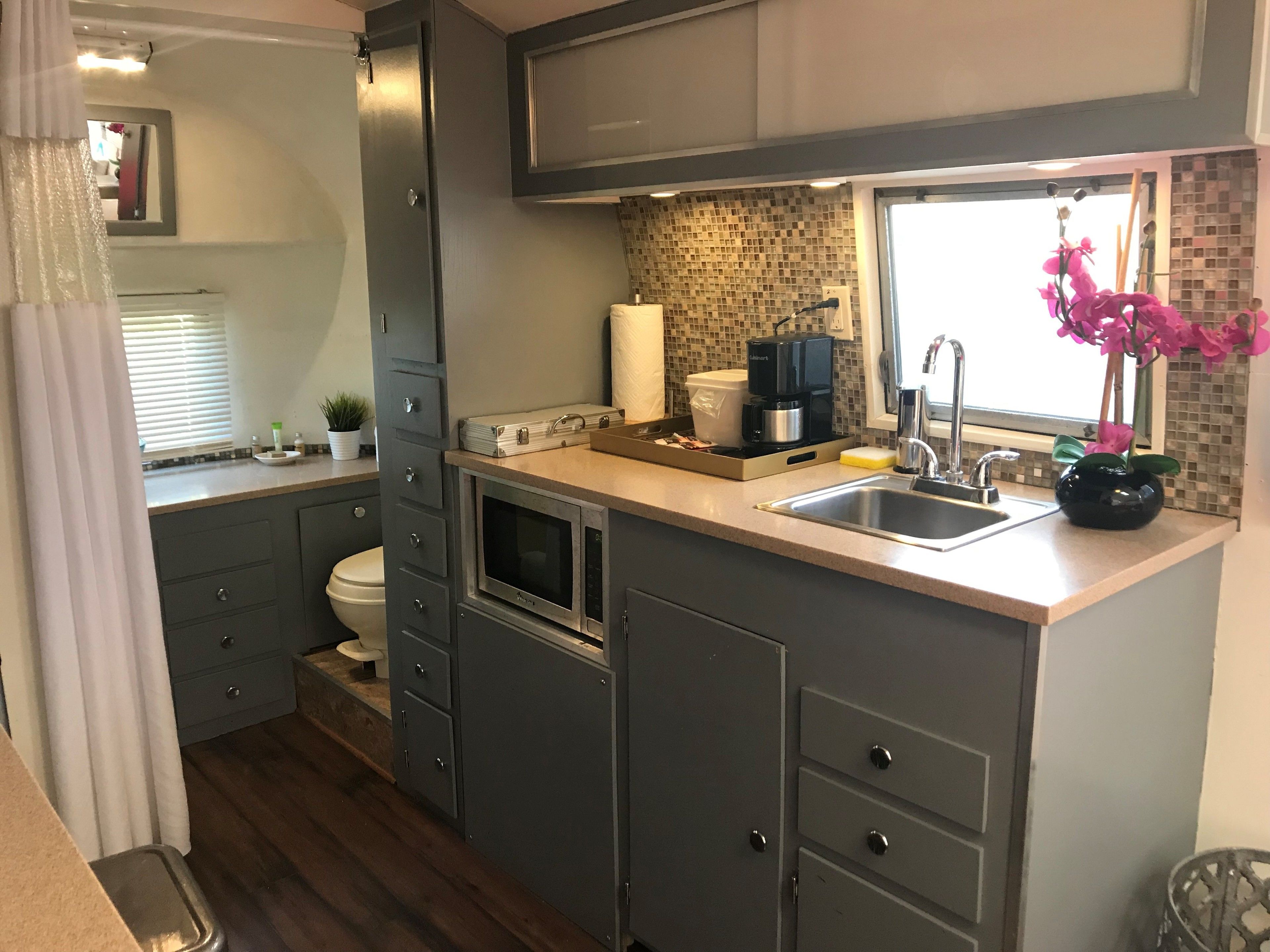 Una cocina compacta equipada con microondas, cafetera y lavabo.