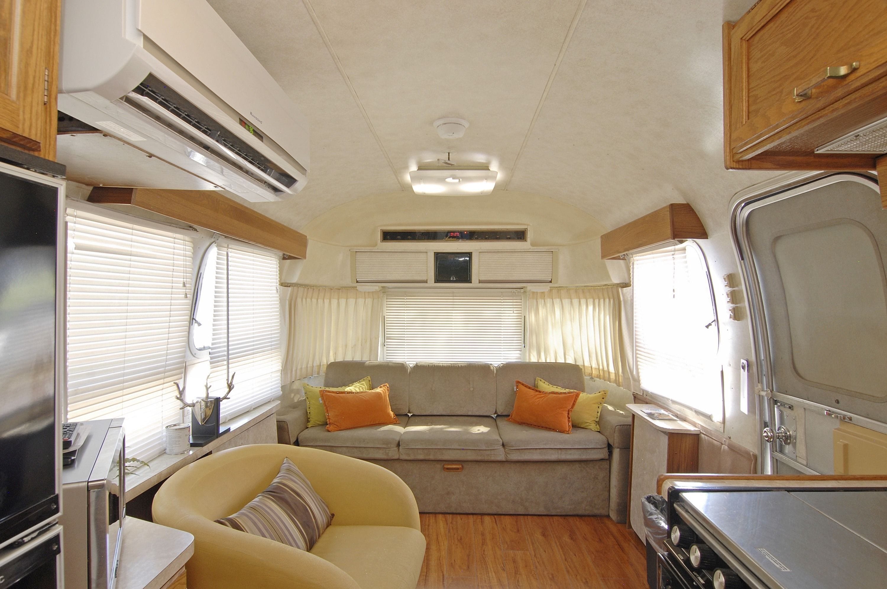 A compact RV interior with a sofa, a small table, and a kitchenette.