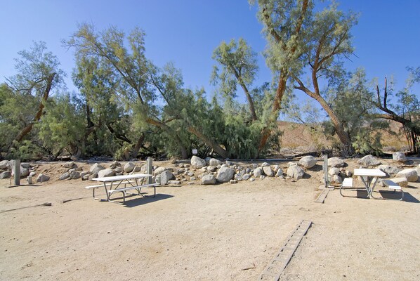 Un espace de pique-nique aménagé dans le désert, avec des tables de pique-nique et un paysage rocheux.