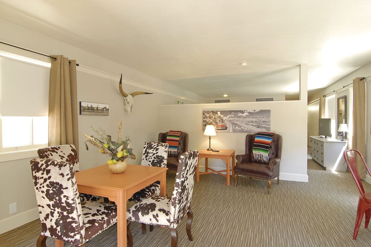 A dining area with a wooden table and chairs, a lamp, and a wall-mounted bull's head decoration.