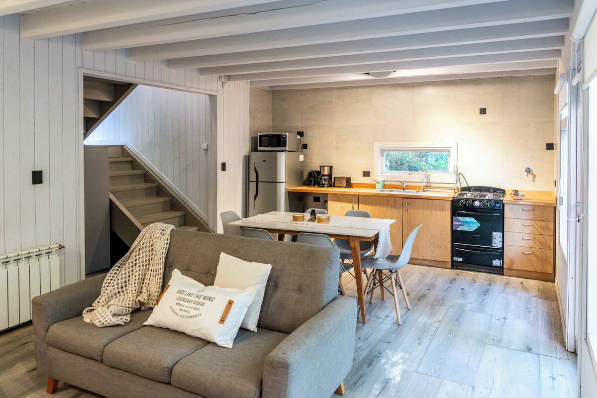 Ein gemütliches Wohnzimmer mit einer Couch, einem Couchtisch und einer Treppe, die zu einer oberen Ebene führt.