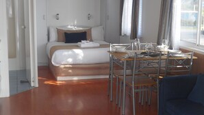 Quarto compacto com cama, uma mesa de jantar com cadeiras e um sofá.