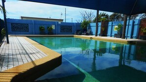 Piscina com deck revestido em mosaico e cerca azul com painéis decorativos.
